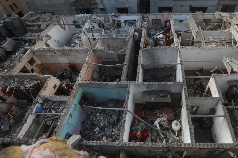 Palestinians look at the destruction after an Israeli strike on residential building in Rafah, Gaza Strip (AP Photo/Ismael Abu Dayyah)