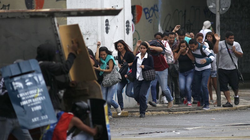 Residents not involved in the protests cover their faces to protect themselves from tear gas, as they cross the street during clashes between security forces and anti-government demonstrators in Caracas, Venezuela, Wednesday, June 7, 2017. The protest movement has claimed more than 60 lives as it enters its third month. Picture by Ariana Cubillos, Associated Press&nbsp;
