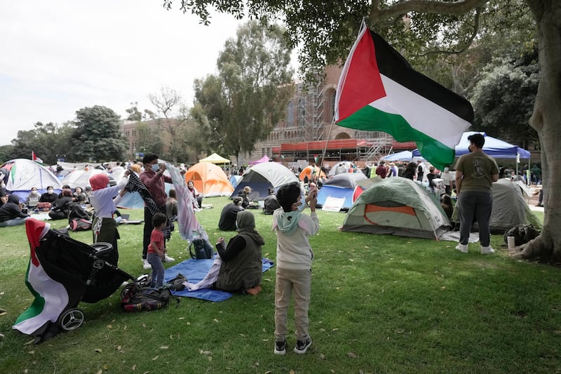 A boy waves a Palestinian flag at an encampment on the University of California, Los Angeles campus (Jae C Hong/AP)