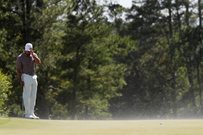 Tiger Woods shields his face from the blowing sand on the 18th hole during the second round of the Masters (Ashley Landis/AP)