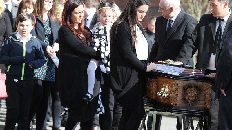Michael McGibbon&#39;s wife Joanne and her children stand over her husband&#39;s Michael&#39;s coffin t his funeral yesterday  
