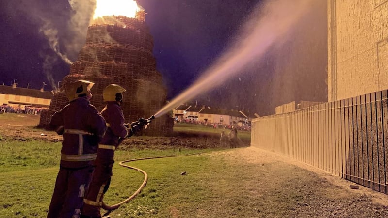 Firefighters dousing blocks of flats with foam at Corcrain Green in Portadown to prevent them from catching fire after a bonfire was lit on Wednesday night 