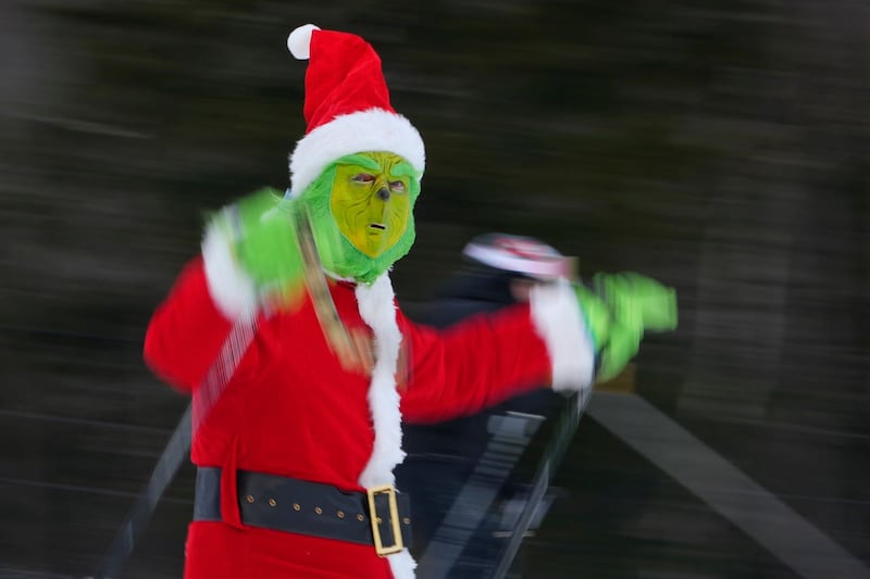 A skier dressed as the Grinch wearing a Santa Claus outfit skis for charity at the Sunday River Ski Resort in Newry, Maine