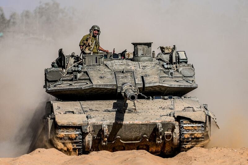 Israeli soldiers drive a tank at a staging ground near the border with the Gaza Strip (AP)