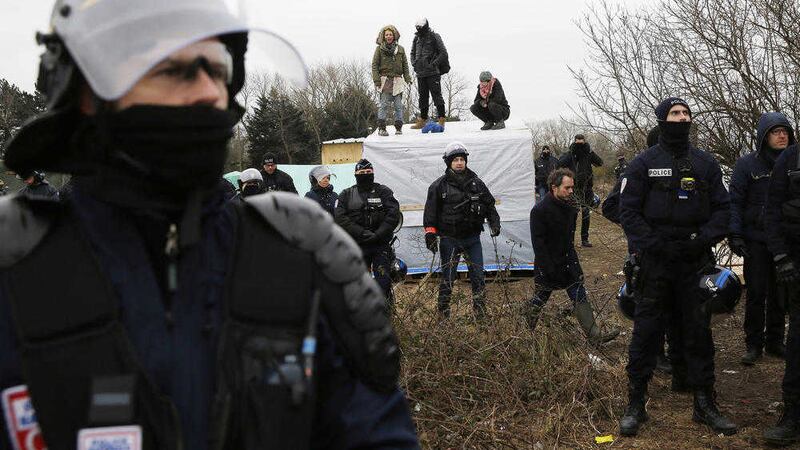 Police surround activists standing on the roofs of dwellings in an attempt to prevent them from being dismantled in a makeshift refugee camp near Calais, France 