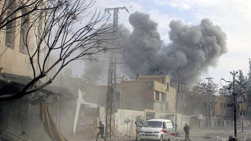 A plume of smoke rises while civil defence workers arrive at the scene of an attack after airstrikes hit a rebel-held suburb near Damascus, Syria last week 