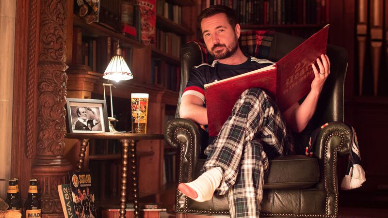Compston, wearing a Scotland jersey and tartan pyjama trousers, reads the story next to a pint of Tennent’s beer and a photo of Archie Gemmill.