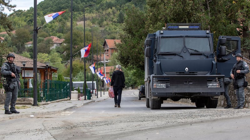 A local Serb man walks past Kosovo police officers securing the area around the Banjska monastery in the village of Banjska, Kosovo (Visar Kryeziu/AP)