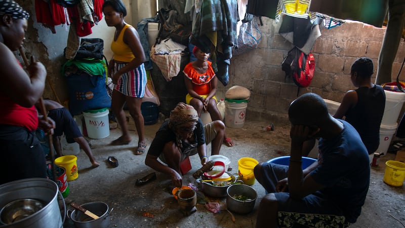 A woman prepares food at a shelter for families displaced by gang violence in Port-au-Prince (Odelyn Joseph/AP)