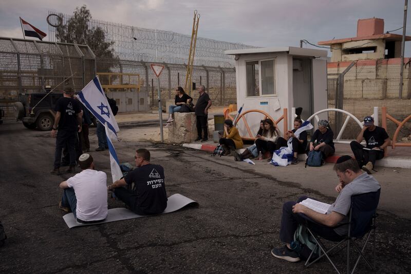 People sit in front of a gate at the Nitzana border crossing with Egypt in southern Israel, protesting against allowing humanitarian aid to enter Gaza until all the hostages are released (Leo Correa/AP)