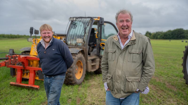 Jeremy Clarkson and Kaleb Cooper standing in front of a JCB