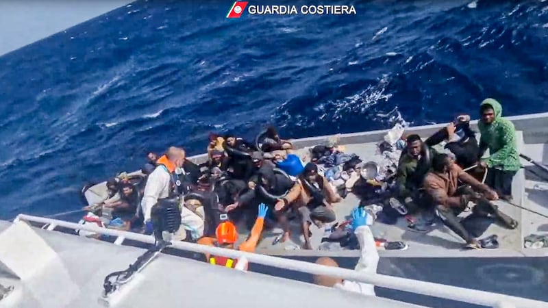 In this image taken from a video released by the Italian Coast Guard, a boat with migrants is approached by a rescue operation off the island of Lampedusa in the Mediterranean Sea (Guardia Costiera/AP)