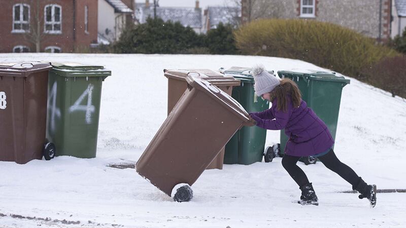 Struggling to get the bin out in Lisburn yesterday as snow began to cover the north. Photo: Mark Marlow