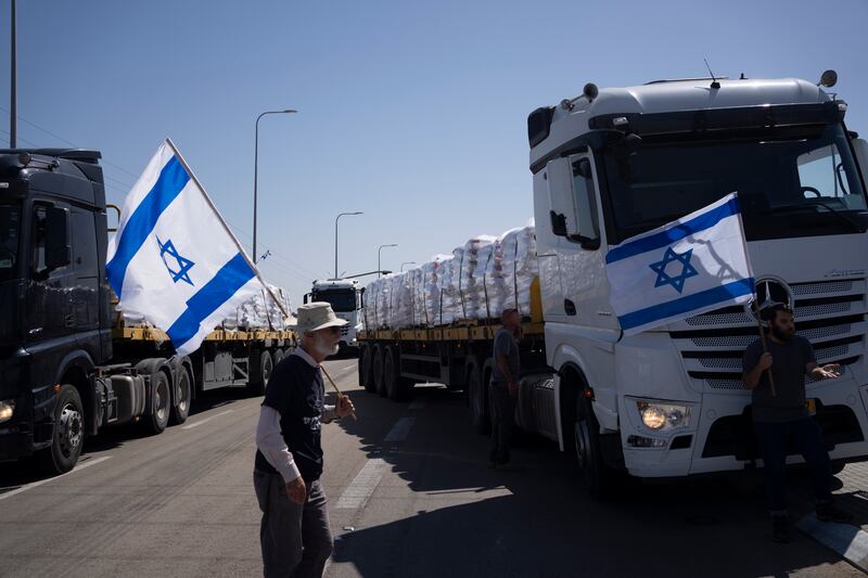 Holding Israeli flags, people stand in front of trucks carrying humanitarian aid as they try to stop them from entering the Gaza Strip in an area near the Kerem Shalom border crossing (AP Photo/Leo Correa)