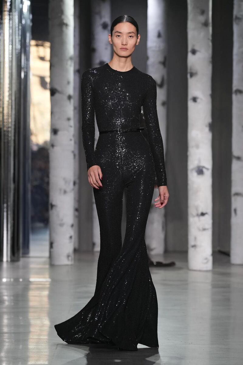 Model on catwalk wearing black sequin jumpsuit, Michael Kors