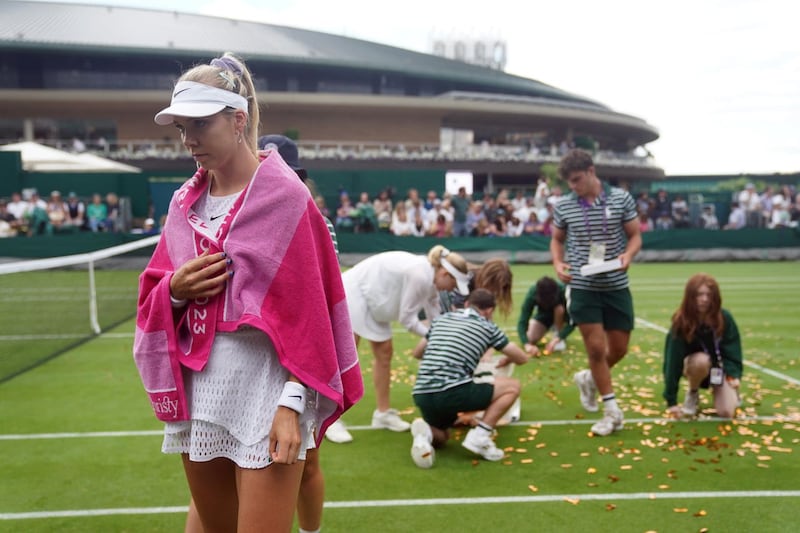 Katie Boulter walks away as ground staff clear confetti from court 18