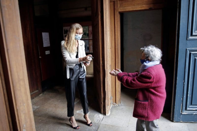 A woman offers hand gel to a worshipper before entering Saint Roch church in Paris last weekend. France is gradually lifting its Covid-19 lockdown, with public worship looking very different. A Drumalis seminar series starting next week will explore what church will be like when collective worship eventually resumes in Ireland. Picture by AP Photo/Francois Mori 