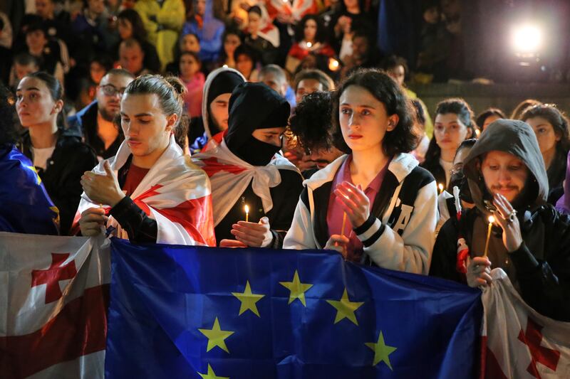 Demonstrators with Georgian and EU flags holding candles stand in front of the Kashveti Church of St George (Zurab Tsertsvadze/AP)