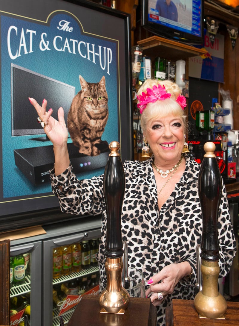 Actress Julie Goodyear, known for portraying pub landlady Bet Lynch in Coronation Street, pulls pints behind a bar