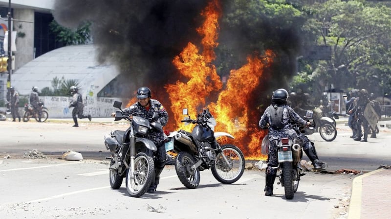 Venezuelan Bolivarian National police move away from the flames after an explosion at Altamira square during clashes against anti-government demonstrators in Caracas Picture: Ariana Cubillos/AP 