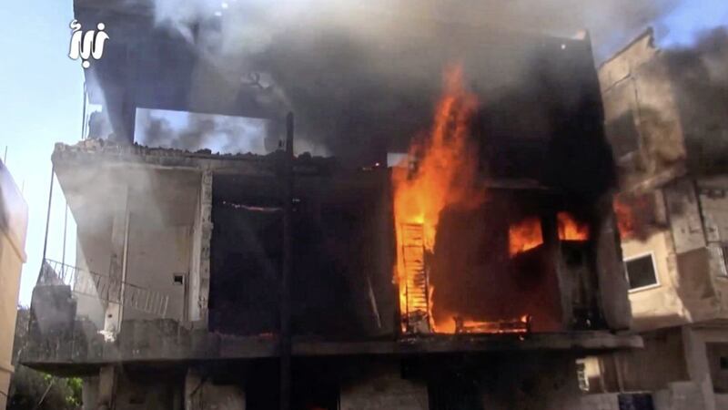 This frame grab from video provided by Nabaa Media shows flames and black smoke rising from a building that was hit by Syrian government forces bombardment, in Daraa city, southern Syria. Picture by Nabaa Media, via Associated Press 