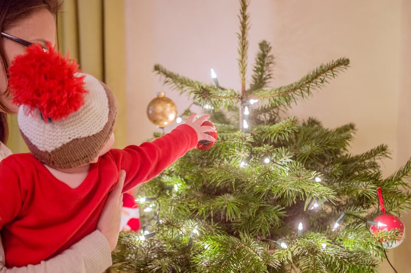 A young child touches a bauble on a Christmas tree