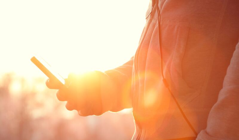 Man holding smartphone in the sun.