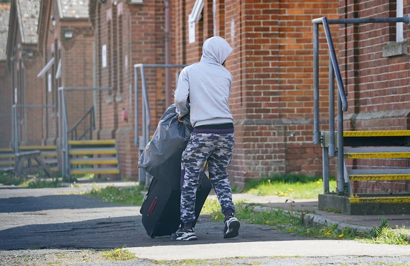 A man thought to be a migrant moves his belongings while he is housed at Napier Barracks in Folkestone, Kent