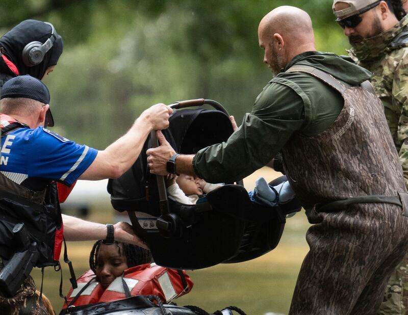 A child in a car seat is taken out of a boat as residents are evacuated by boat from their homes by Montgomery County Sheriff’s Office deputies (Houston Chronicle via AP)