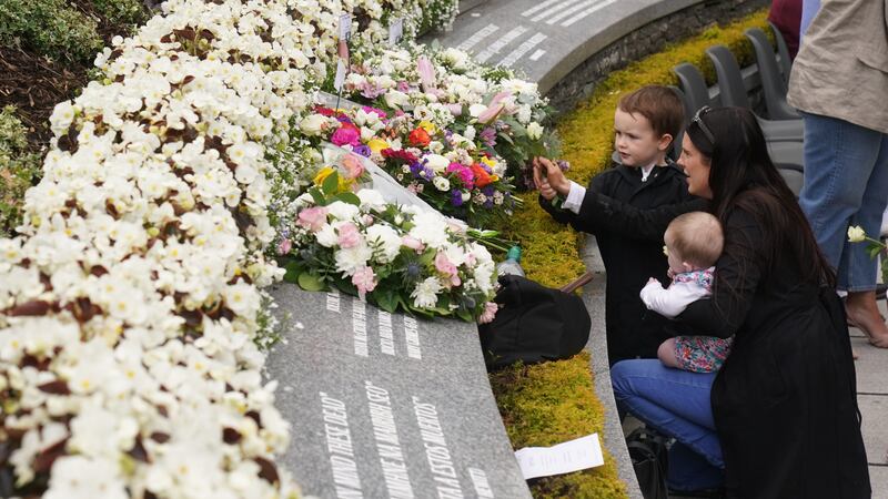 Bernadette Duffy (right) with son Daithi, aged four, and daughter Saoirse, aged four months, place a flower during a service to mark the 25th anniversary of the bombing that devastated Omagh in 1998 (Brian Lawless/PA)