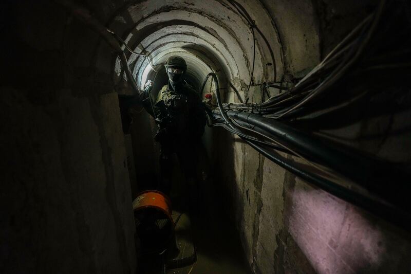 An Israeli soldier holds a light inside a tunnel underneath the UNRWA compound (AP)