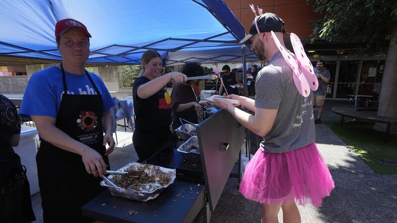 Ben Betts is dressed in a pink tutu and fairy wings as he is served a democracy sausage at a polling place in Redfern, Sydney (Rick Rycroft/AP)