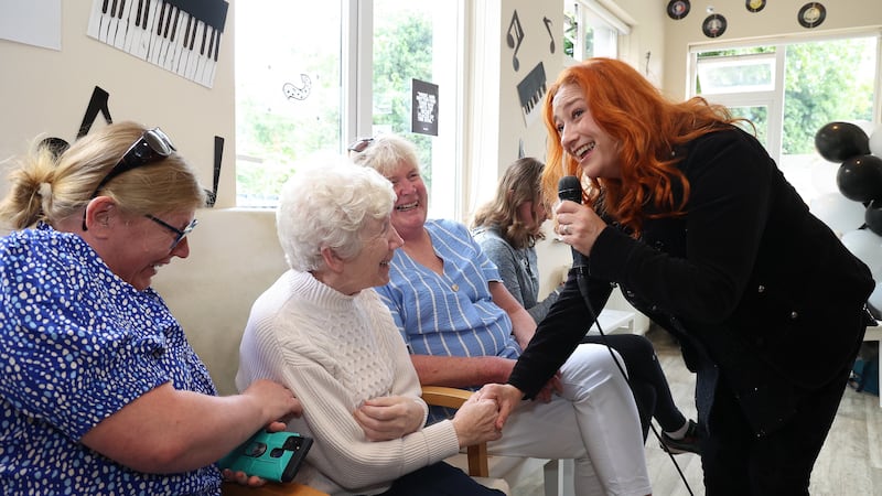 Agnus McCabe with her daughters, Roisin and Siobhan, listen to Niamh Kavanagh and the Mobile Music Machine perform at Asgard Lodge Nursing Home in Arklow, Co Wicklow (Julien Behal Photography/PA)