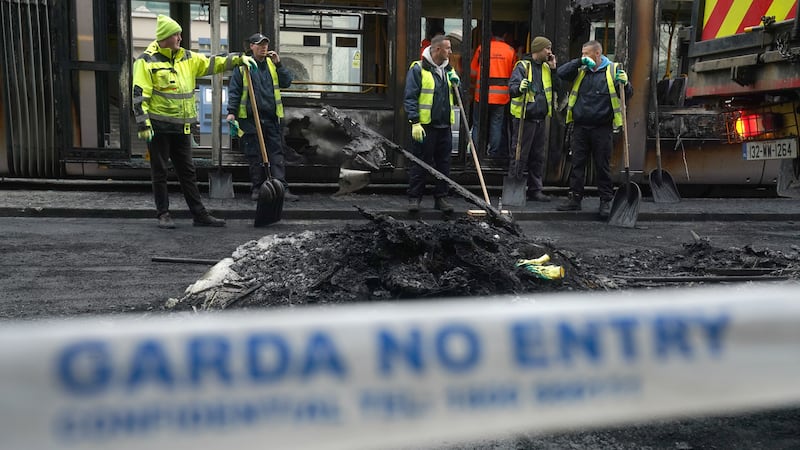 Debris is cleared from a burned out Luas and bus on O’Connell Street in Dublin, in the aftermath of violent scenes in the city centre on Thursday evening (Brian Lawless/PA)
