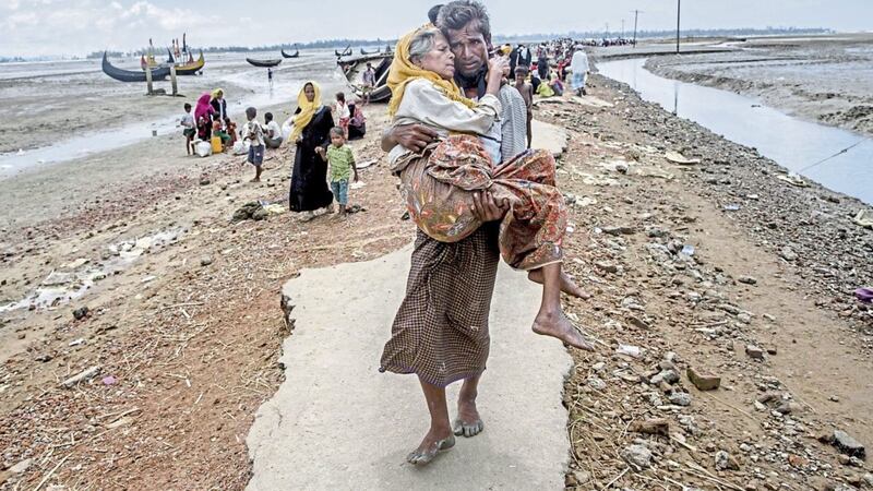 Rohingya Muslim man Abdul Kareem walks towards a refugee camp carrying his mother Alima Khatoon after crossing over from Myanmar into Bangladesh on Saturday PICTURE: Dar Yasin/AP 