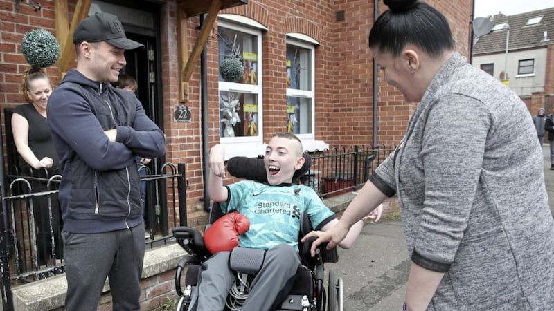 Pearse Campbell (18) was stunned when boxer Carl Frampton dropped by to see him yesterday. The teenager returned from London last week where he had a specialist back brace fitted, which was partly funded by the boxer. Also pictured are neighbour Jeanne Kelly and his mother, Aisling. Picture by Declan Roughan 