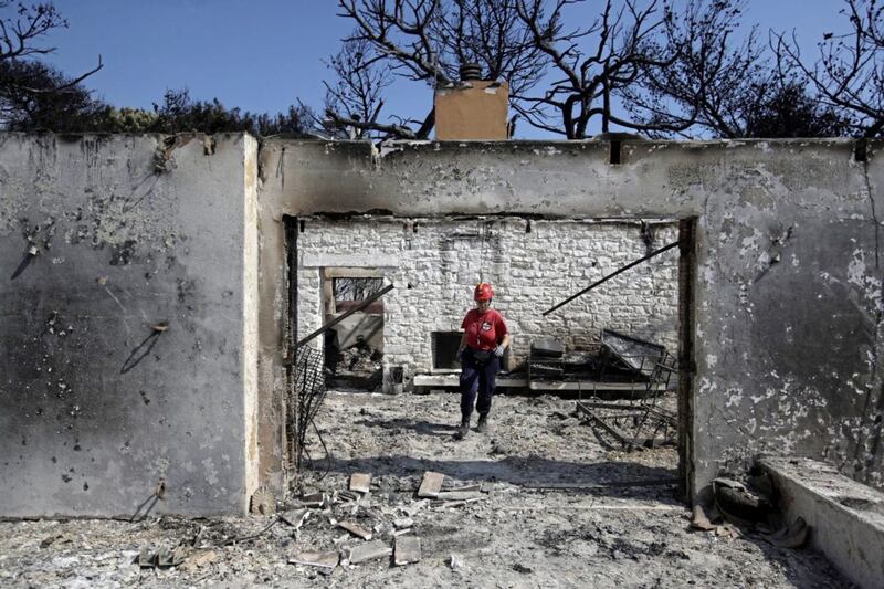 A member of a rescue team searches a burned house in Mati, east of Athens, following the deadliest wildfires to hit Greece in decades. Picture by Thanassis Stavrakis, Associated Press