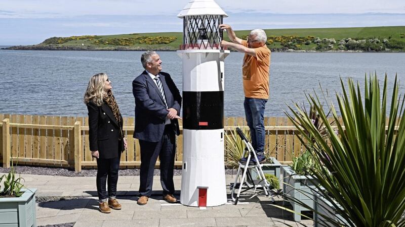 A 10ft tall lighthouse built by prisoners in Maghaberry will help shine a spotlight on the convalescent work of the cancer charity Hope House. The structure has been erected at Hope House Cottage on the beach at Browns Bay at Islandmagee. Looking on as charity volunteer Sam McCullough makes a final adjustment to the lighthouse, are David Savage, Governor of Maghaberry Prison and Dawn McConnell, founder of the Hope House charity. Picture by Michael Cooper 