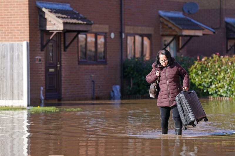 Woman walking through floodwater carrying suitcase