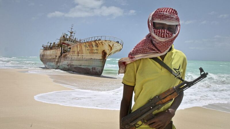 FILE - In this Sunday, Sept. 23, 2012 file photo, masked Somali pirate Hassan stands near a Taiwanese fishing vessel that washed up on shore after the pirates were paid a ransom and released the crew, in the once-bustling pirate den of Hobyo, Somalia. Somali pirates have seized a small boat, kidnapped its Indian crew members, and are taking the vessel to the Eyl area of northern Somalia, an investigator said Monday, April 3, 2017, the latest vessel targeted by the region's resurgent hijackers. (AP Photo/Farah Abdi Warsameh, File).