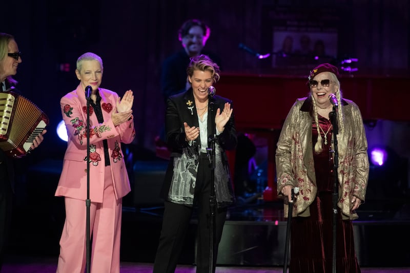 Annie Lennox, left, and Brandi Carlile, centre, applaud Joni Mitchell after she sang at the concert (Kevin Wolf/AP)