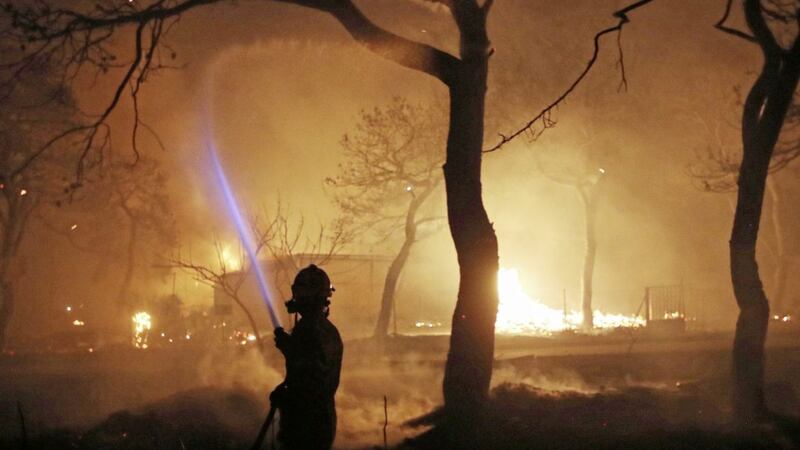 A firefighter sprays water on the fire in the town of Mati, east of Athens Picture by Thanassis Stavrakis/AP 