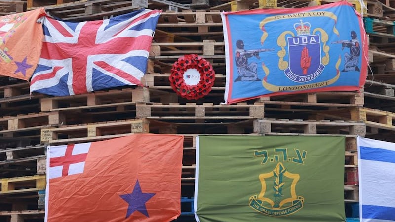 &nbsp;Flags (clockwise from top left) a Union flag, a loyalist paramilitary UDA flag, the Israeli Defence Force and an orange order flag, with a Royal British Legion poppy wreath, hung on a large bonfire being built to mark the Catholic Feast of the Assumption in the Bogside area of Derry. Picture date: Sunday August 15, 2021.