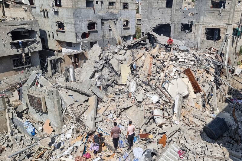Palestinians look at the destruction after an Israeli air strike in Rafah (Mohammad Jahjouh/AP)