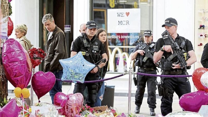 Armed police look at flowers and tributes left in St Ann&#39;s Square in Manchester, exactly a week since the Manchester Arena terror attack took place. Picture by Owen Humphreys, Press Association 