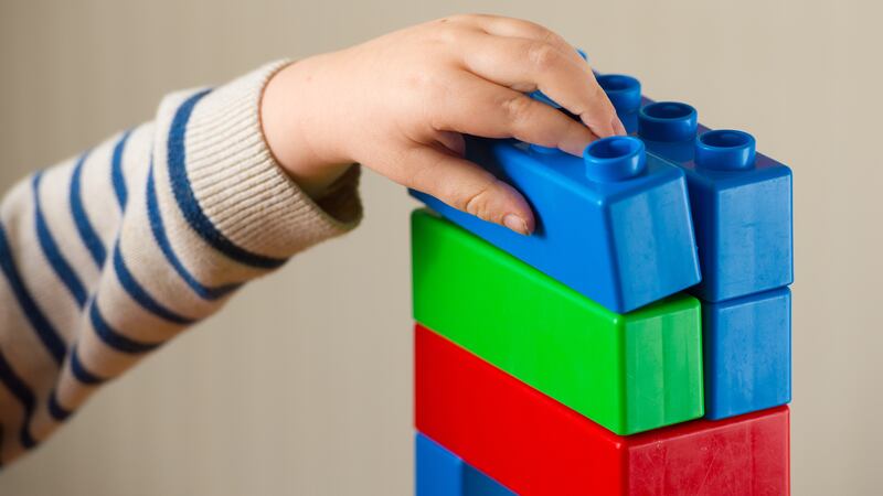 A preschool age child playing with plastic building blocks