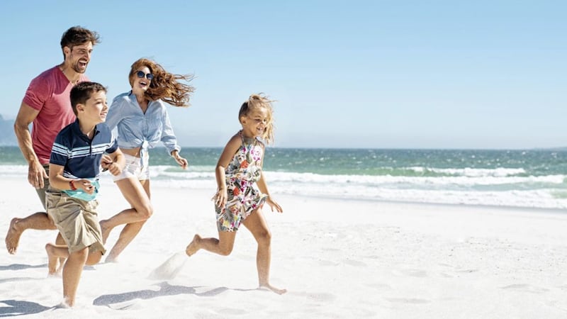 Cheerful young family running on the beach with copy space.&nbsp;