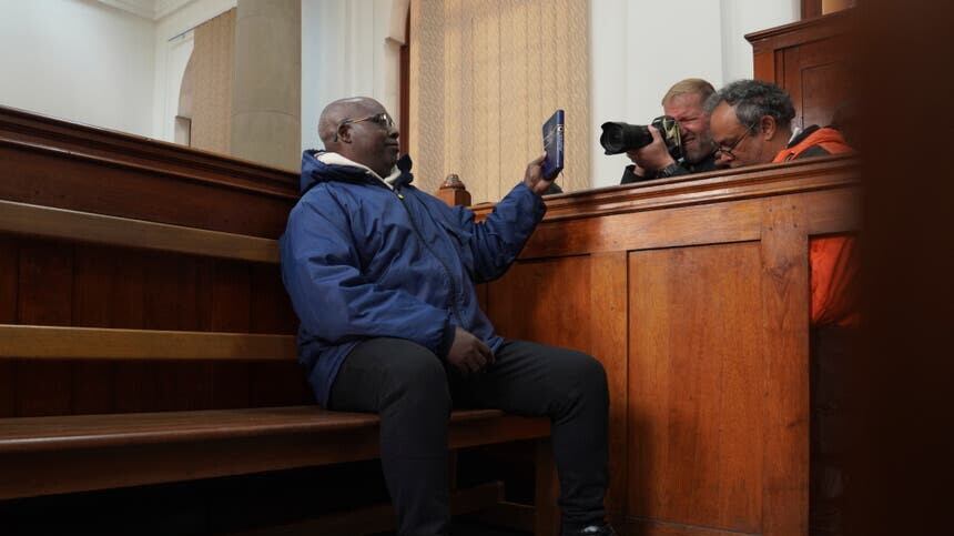 Fulgence Kayishema holds up a book in the magistrates’ court in Cape Town, South Africa (Nardus Engelbrecht/AP/PA)