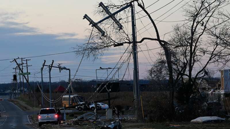 A vehicle sits by the side of the road near damaged power lines (Mark Zaleski/AP)