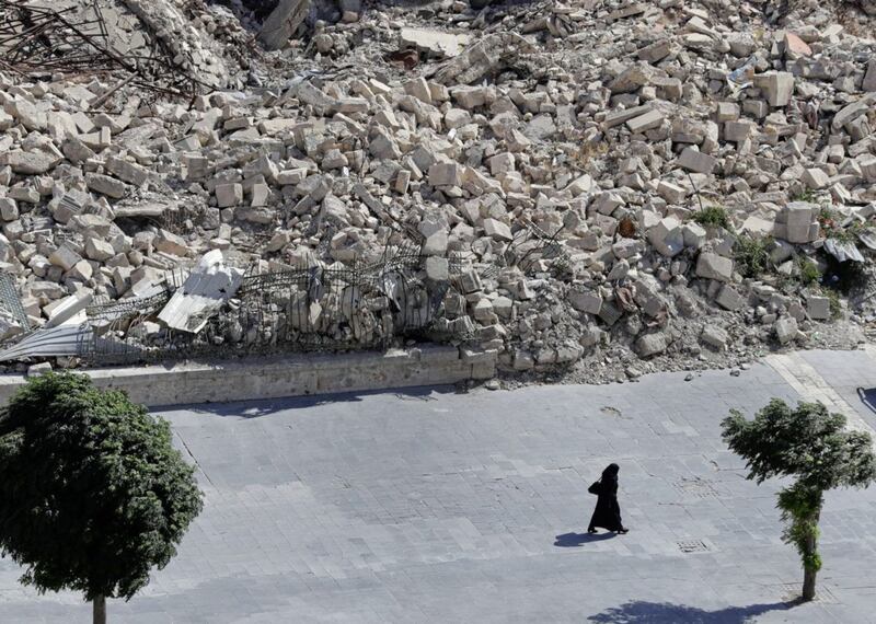A woman walks past the remnants of destroyed buildings in the city of Aleppo, Syria, earlier this year 